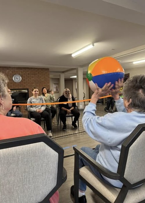 Walden Place Senior Living residents and employees play a game of chair Volleyball together.