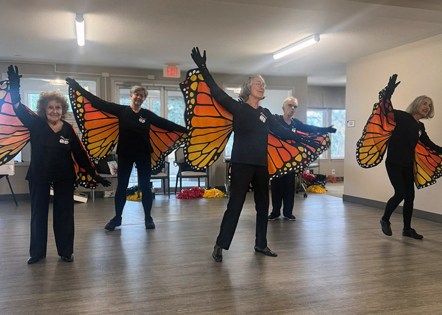 A group of senior women perform in colorful monarch butterfly wings.